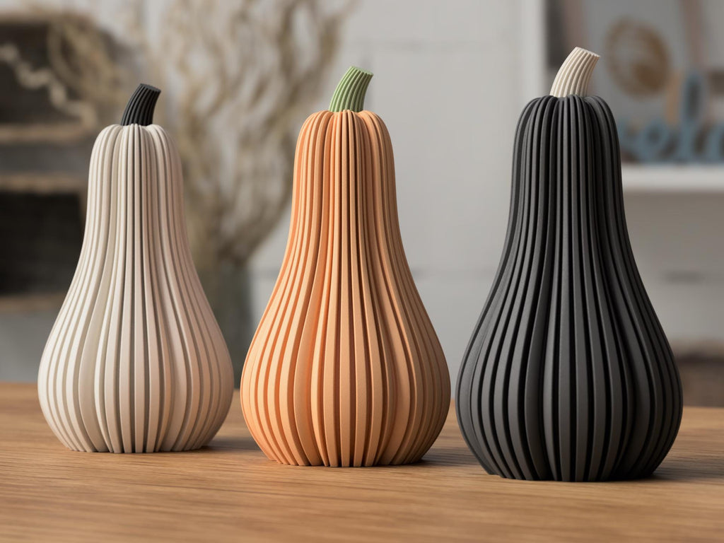 Three decorative gourds in beige, brown, and black on a wooden surface.