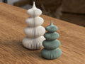 Two ceramic towers, one white and one green, on a wooden surface.