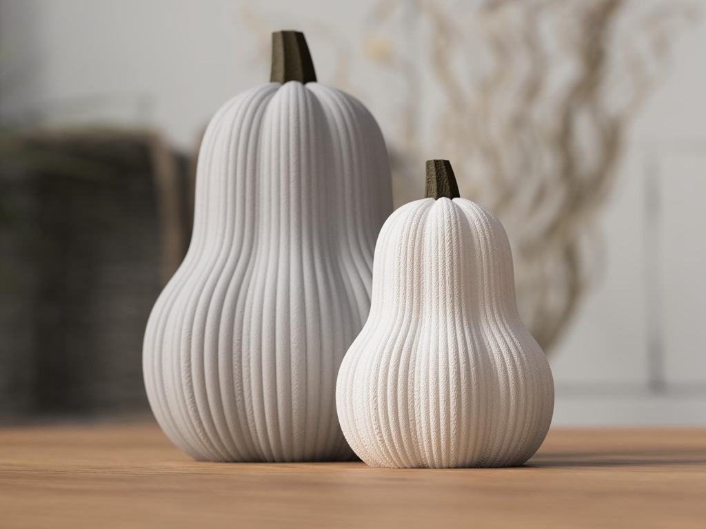 Two ribbed ceramic pumpkins on a wooden surface with a blurred background