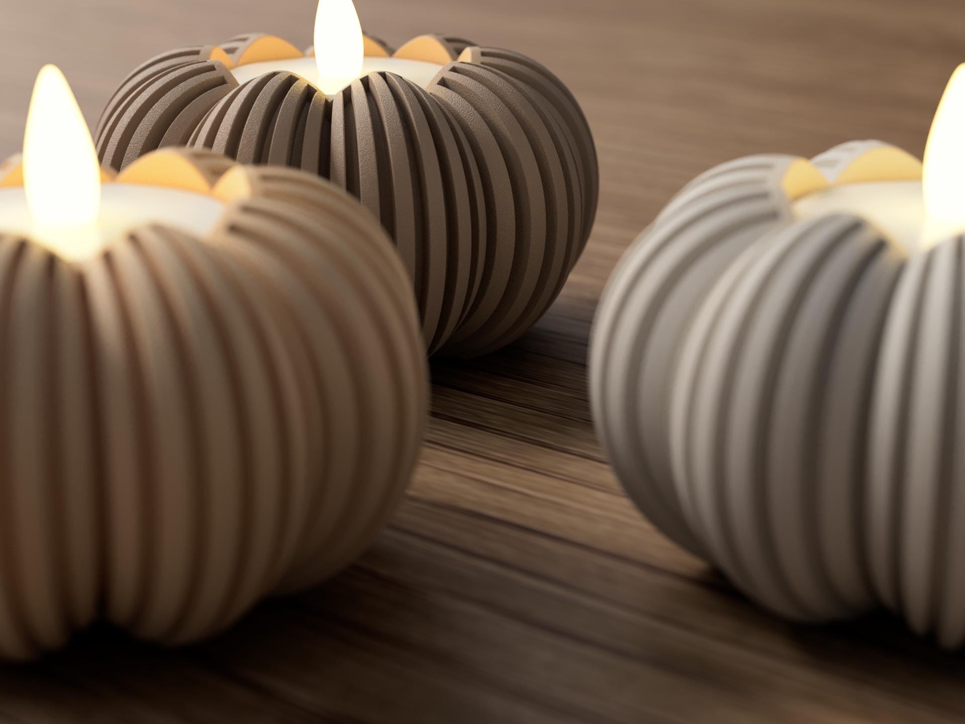 Ceramic pumpkin-shaped candles with lit wicks on a wooden surface