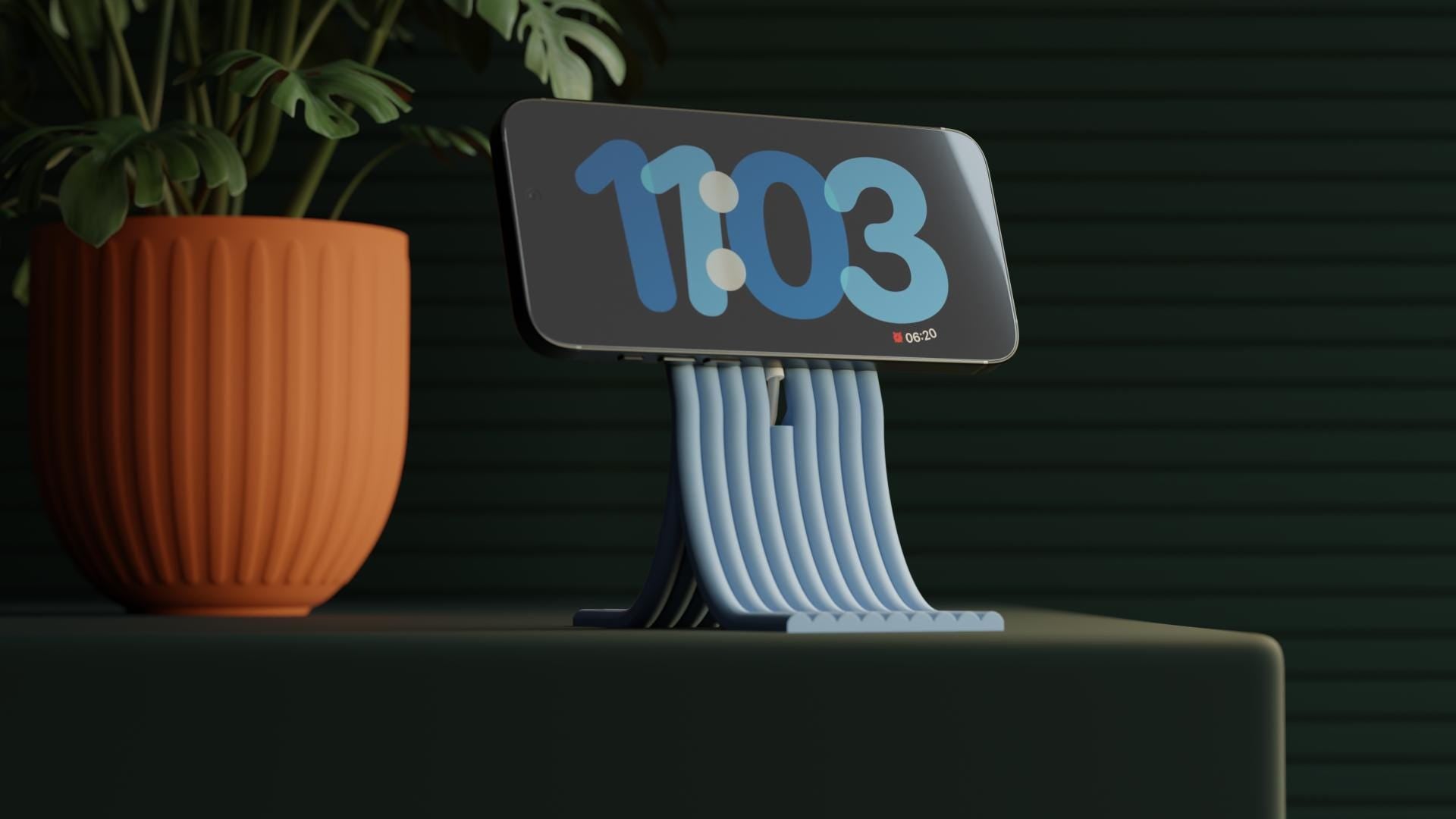 Digital clock with blue display showing time '11:03' next to a potted plant on a dark background