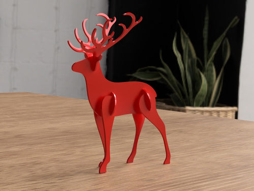 Red deer figurine on a wooden surface with a plant in the background