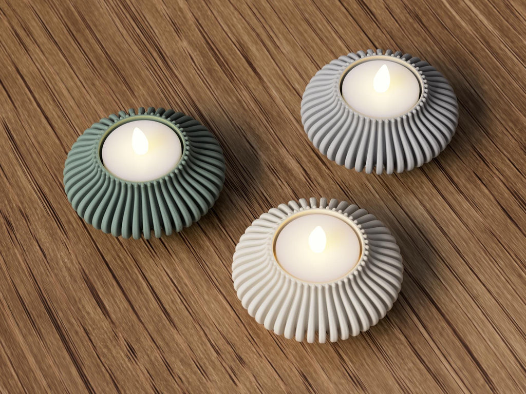 Three decorative candle holders with lit candles on a wooden surface
