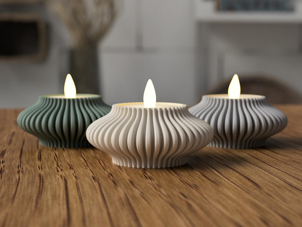 Three ribbed ceramic tealights on a wooden surface with a blurred background