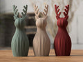 Three decorative vases with antler designs in green, brown, and red on a wooden surface.