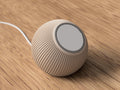 Round beige speaker with ribbed texture on a wooden surface