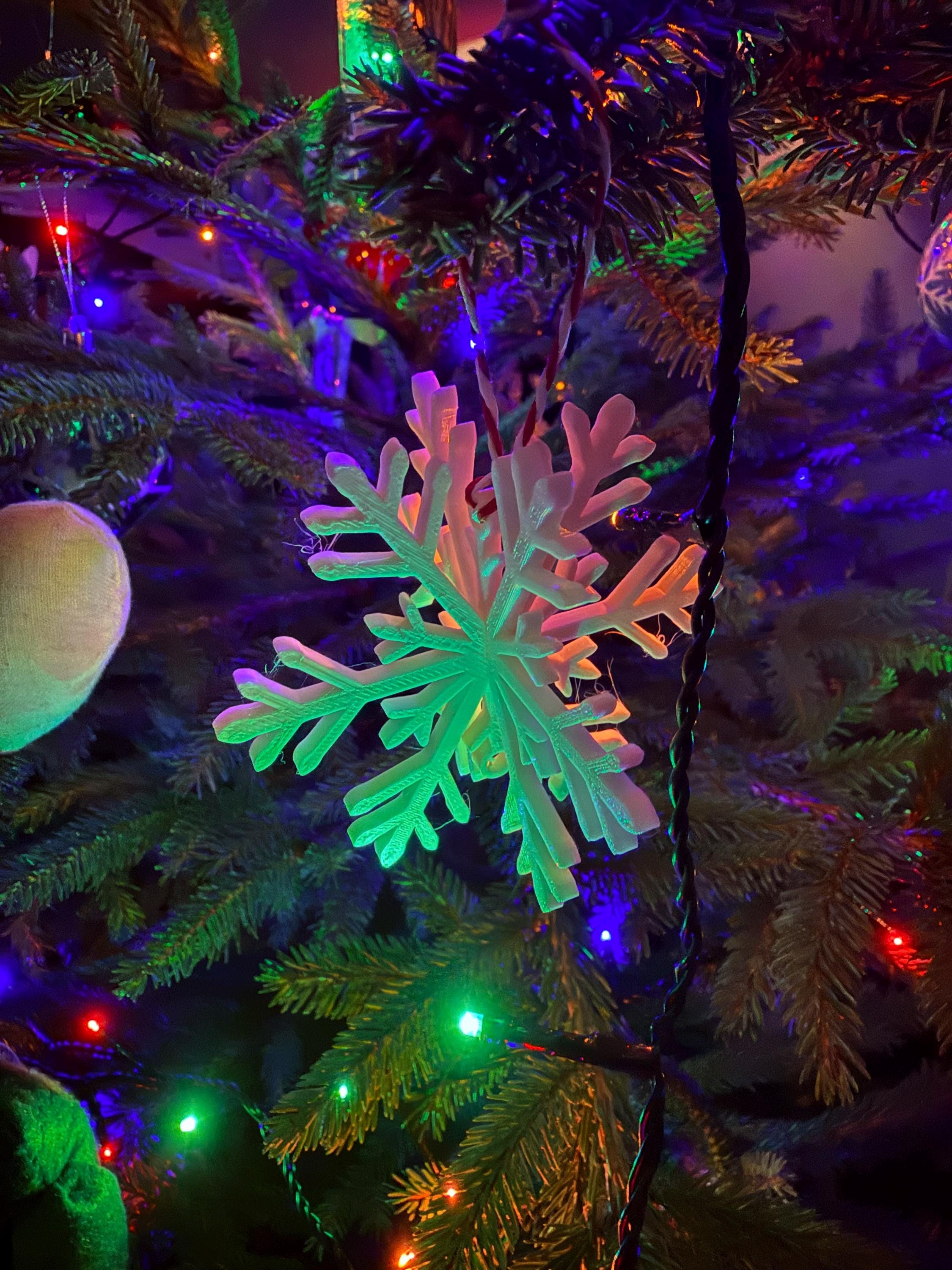 Decorative snowflake ornament on a Christmas tree with colorful lights
