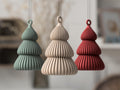 Three textured pendant lights in green, beige, and red hanging against a blurred indoor background.