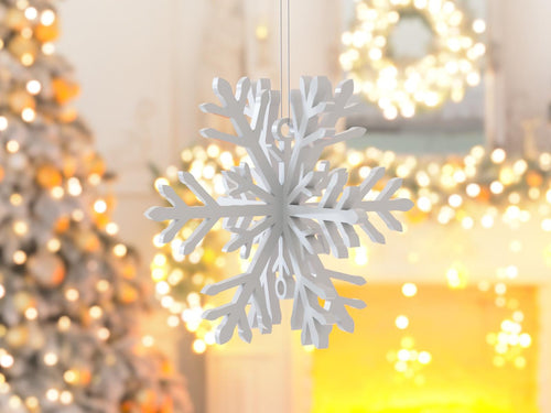 White snowflake ornament with festive lights and decorations in the background