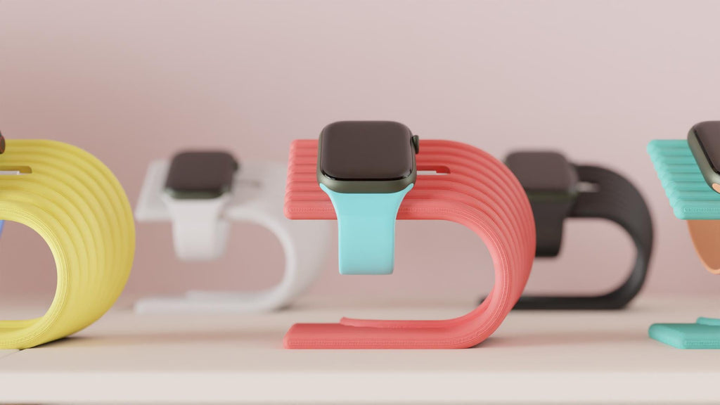 Smartwatch with colorful bands on a stand against a light pink background