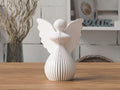 White angel figurine with butterfly wings on a wooden surface