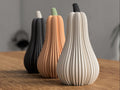 Three decorative gourd-shaped vases in black, brown, and white on a wooden surface.