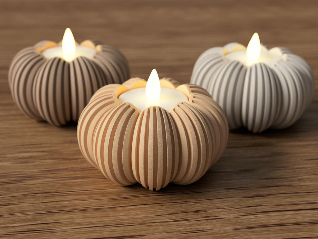 Three striped candle holders with lit candles on a wooden surface