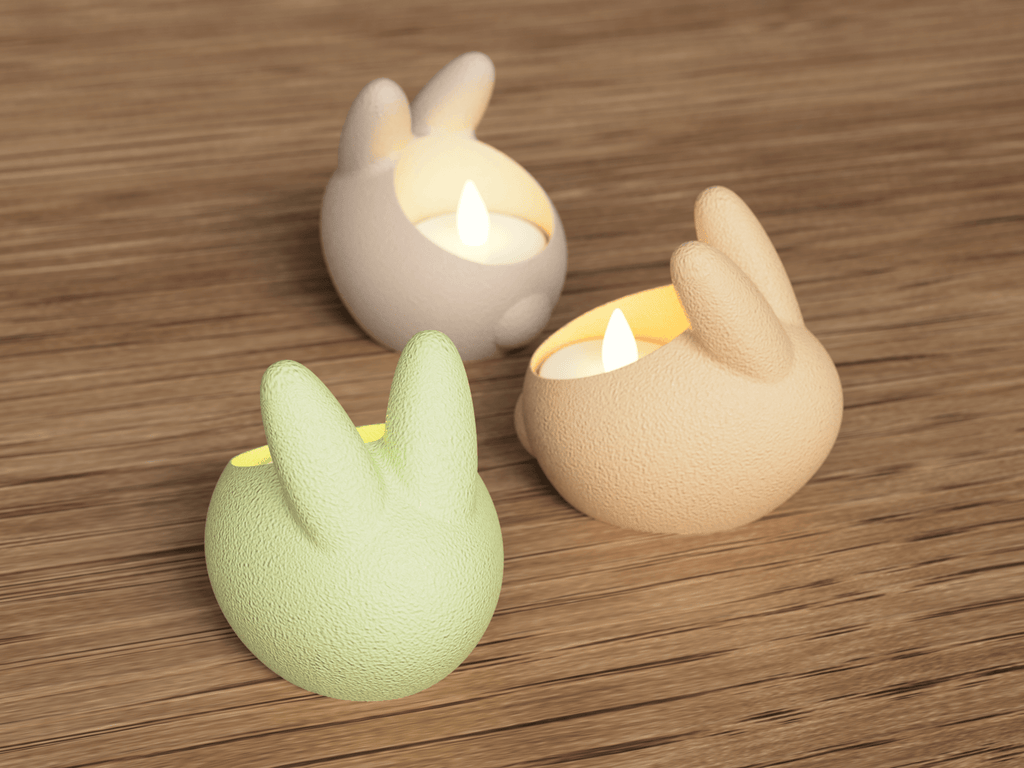 Three rabbit-shaped candle holders with lit candles on a wooden surface