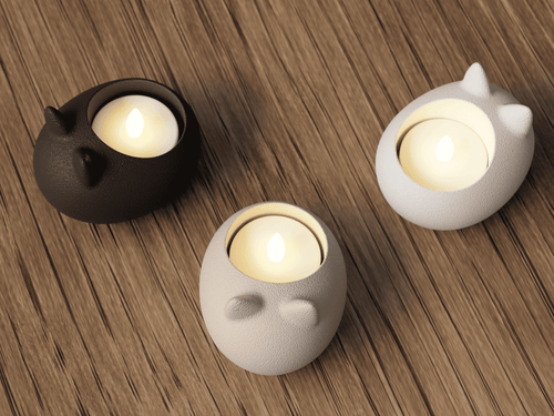 Three cat-shaped candle holders with lit candles on a wooden surface