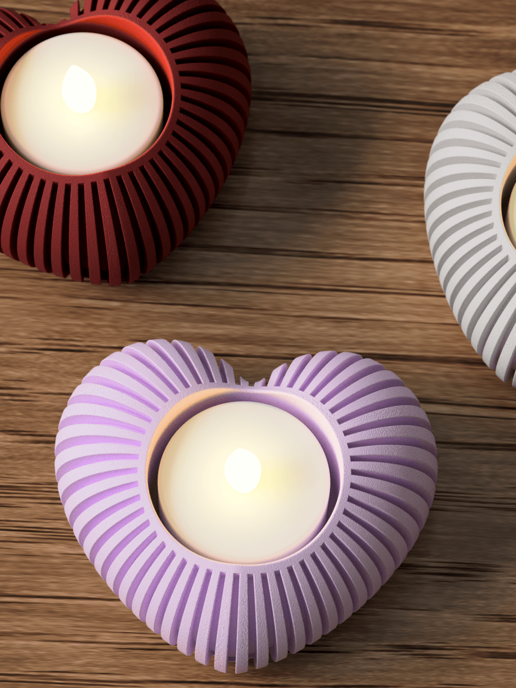 Heart-shaped candle holders in red, purple, and white on a wooden surface.