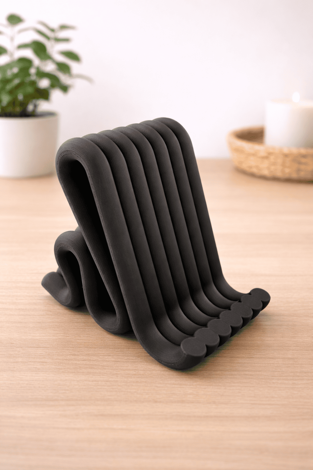 Black phone stand on a wooden surface with a blurred indoor background