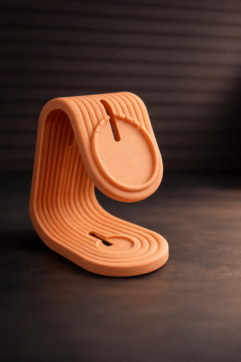 Terracotta-colored phone stand on a dark surface with a dark background