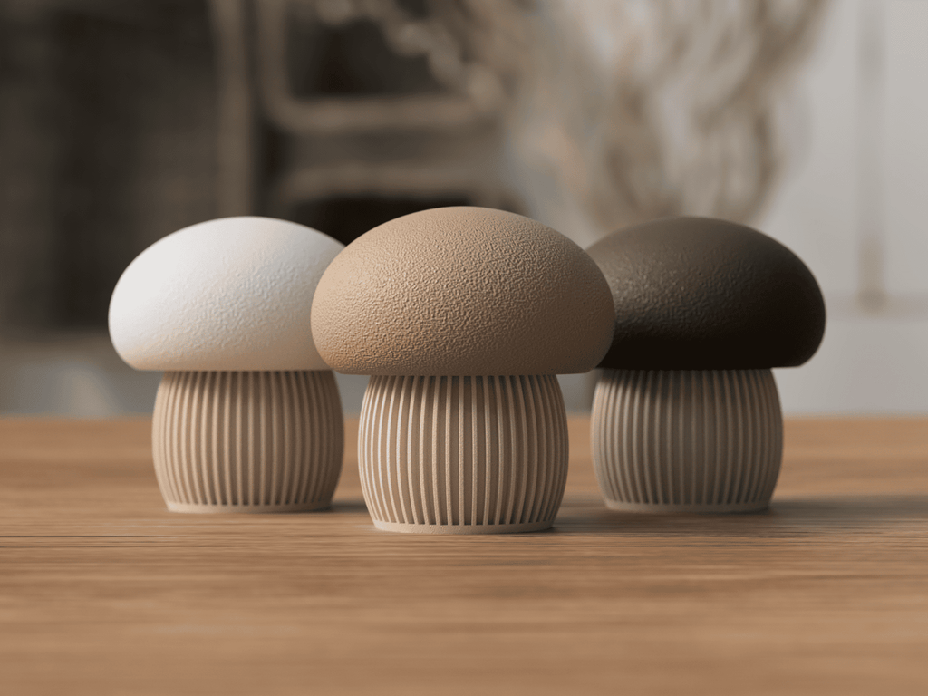 Three mushroom-shaped objects in white, beige, and brown on a wooden surface with a blurred natural background.