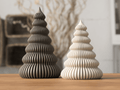 Two decorative Christmas trees made of wood on a wooden surface with a blurred indoor background.