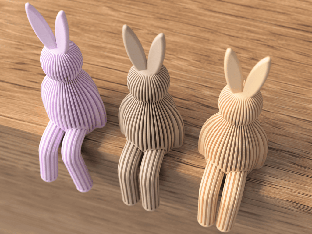 Three rabbit-shaped door stoppers in different colors on a wooden surface