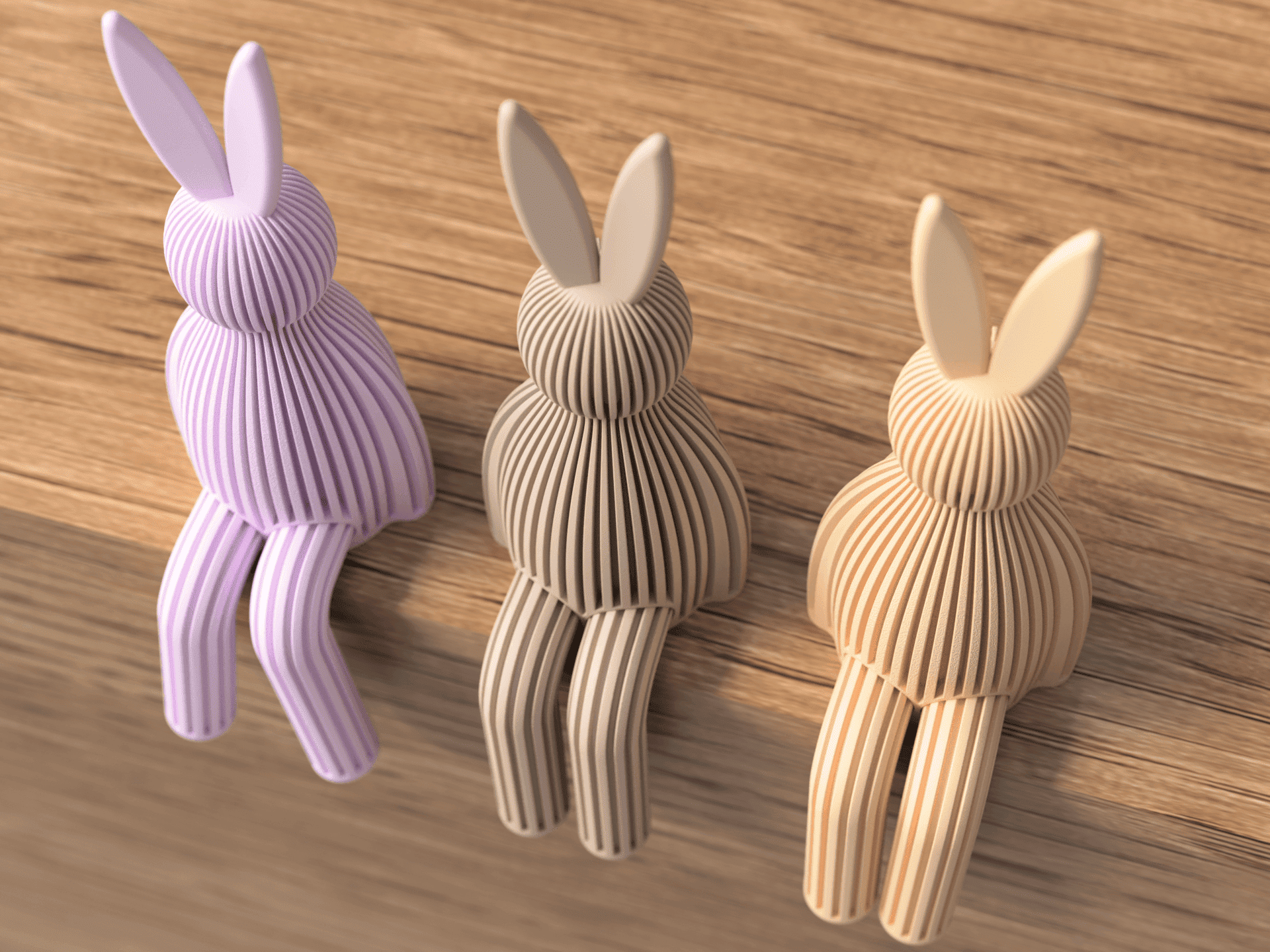 Three rabbit-shaped door stoppers in different colors on a wooden surface