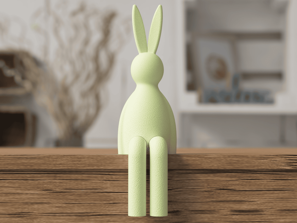 Green rabbit-shaped object on a wooden surface with a blurred indoor background