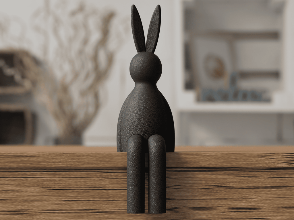 Black rabbit sculpture on a wooden surface with a blurred indoor background