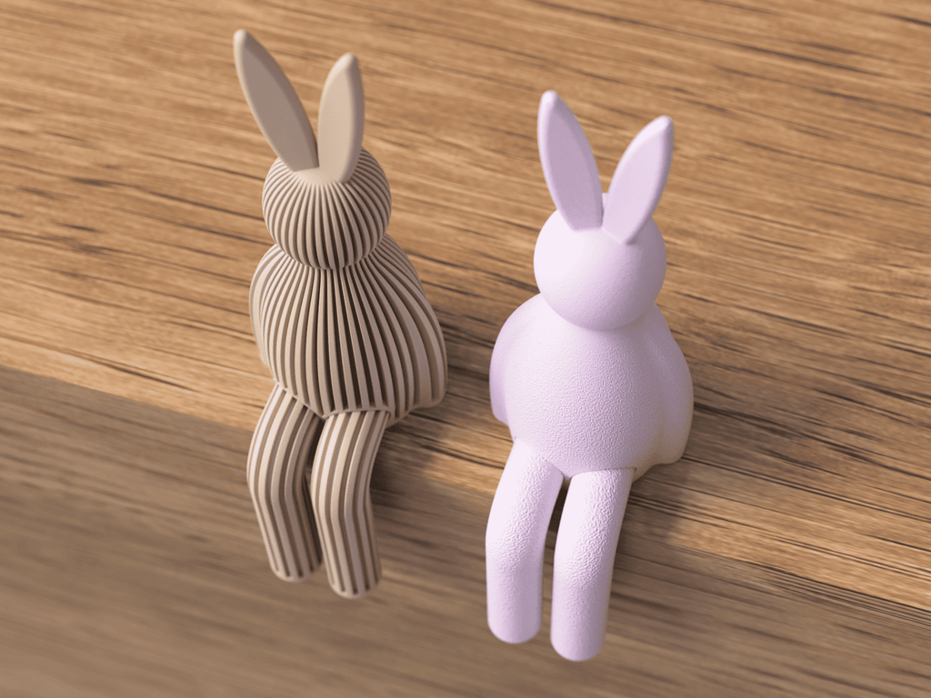 Two rabbit-shaped objects, one brown and one purple, on a wooden surface.