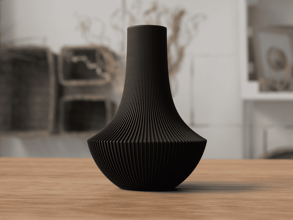 Black textured vase on a wooden surface with a blurred indoor background