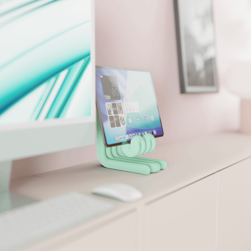 Mint green phone stand on a desk with a computer monitor in the background