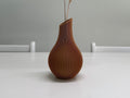 Brown textured vase on a white surface with a gray background