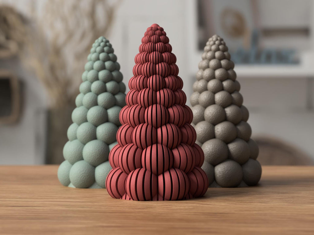 Three textured ceramic trees in green, red, and gray on a wooden surface.
