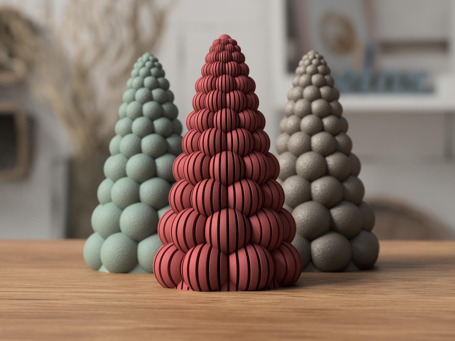 Three textured ceramic trees in green, red, and gray on a wooden surface.
