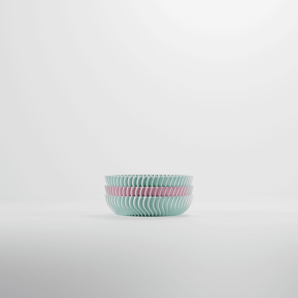 Set of two ribbed ceramic bowls in pastel green and pink on a light gray background