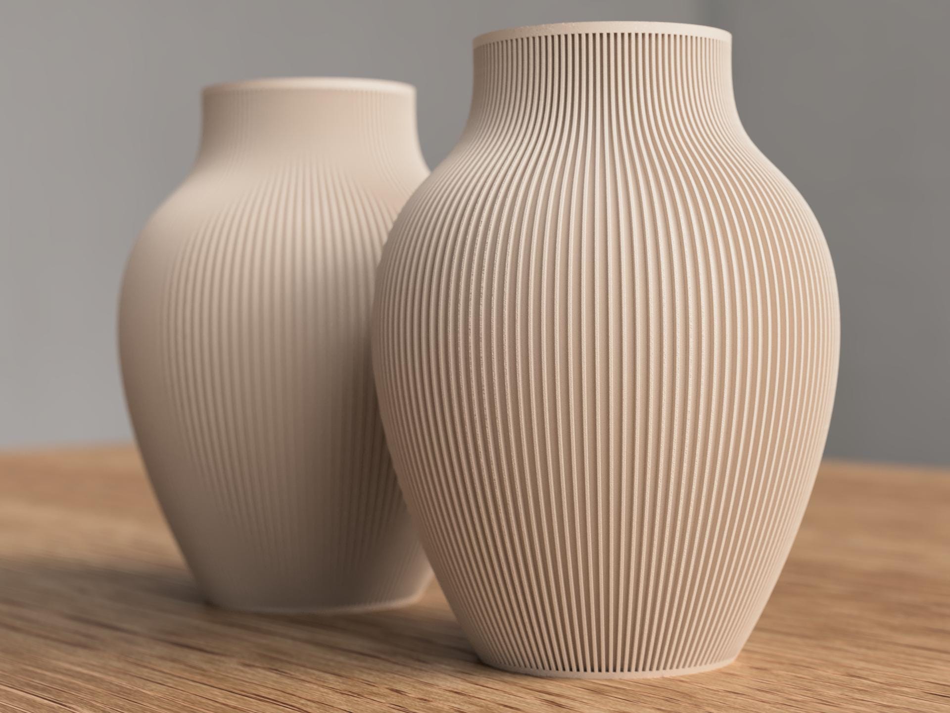 Two beige ceramic vases with textured surfaces on a wooden surface.