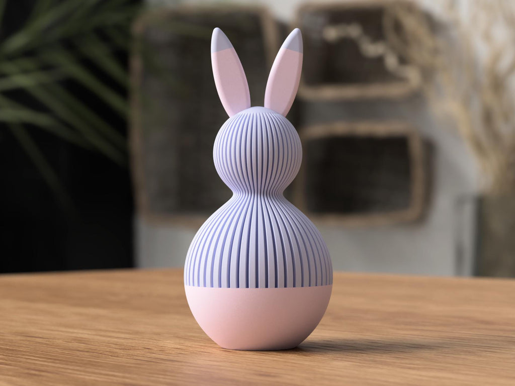 Pink and purple rabbit-shaped object on a wooden surface with a blurred background