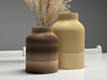 Two textured vases on a white surface with a gray background