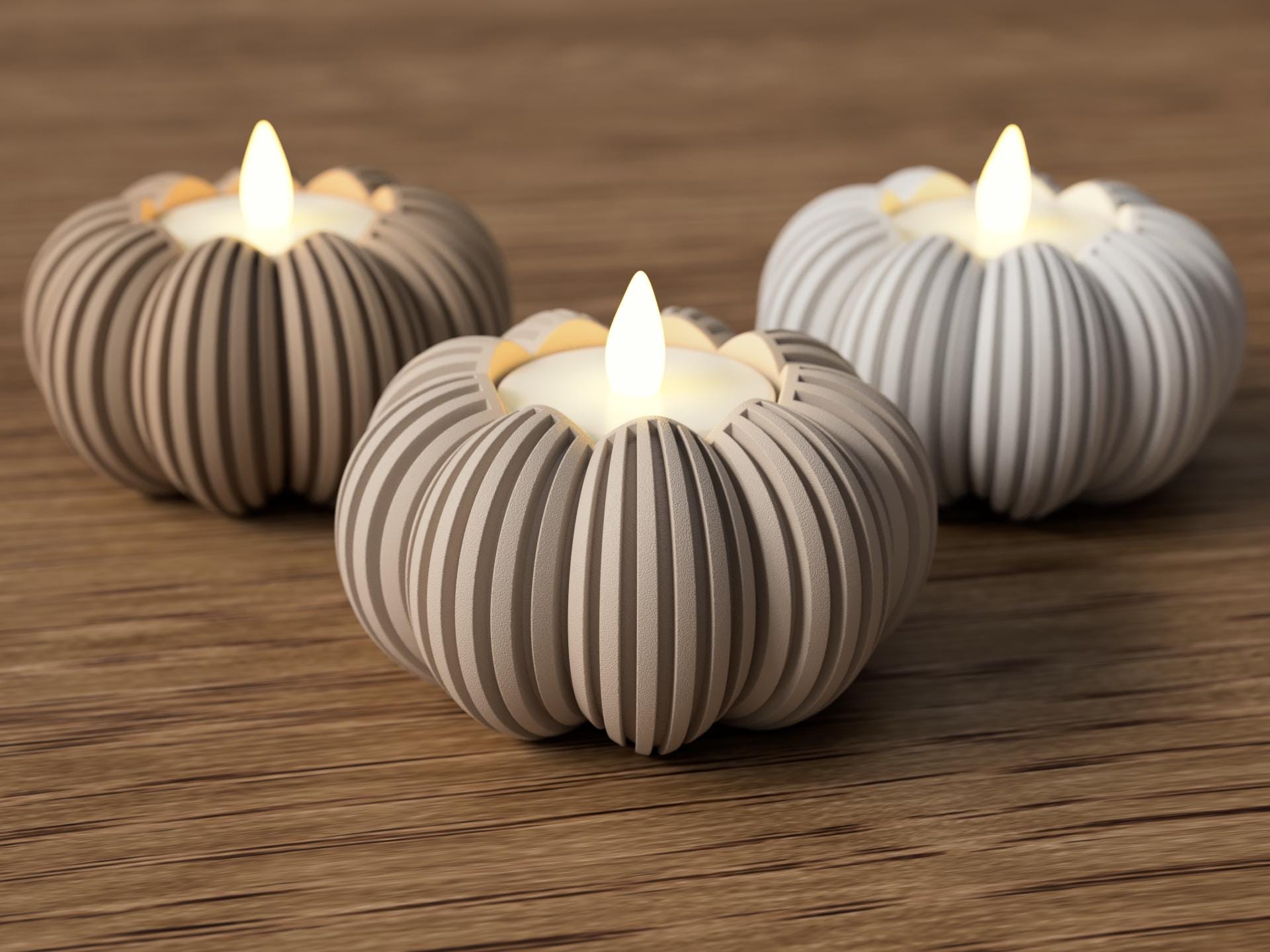 Three striped candle holders with lit candles on a wooden surface
