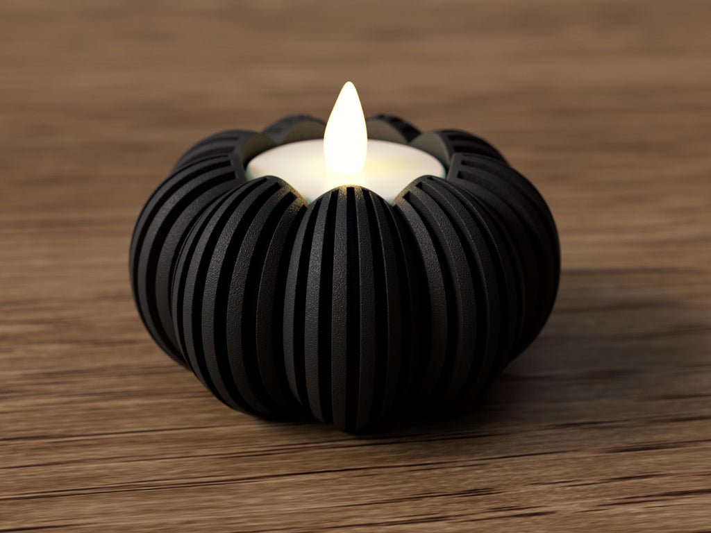 Black ribbed candle holder with a lit candle on a wooden surface