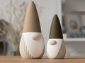 Two decorative gnomes with brown and black hats on a wooden surface.