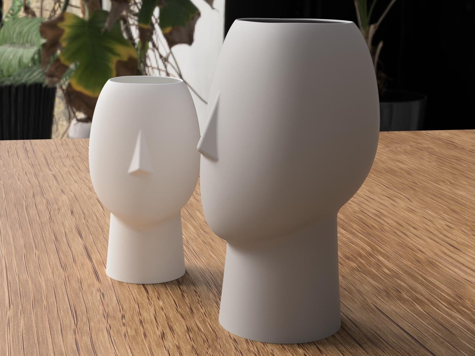 Two white ceramic vases on a wooden surface with blurred greenery in the background
