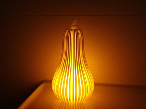 Gourd-shaped lamp emitting a warm glow on a wooden surface with a dark background